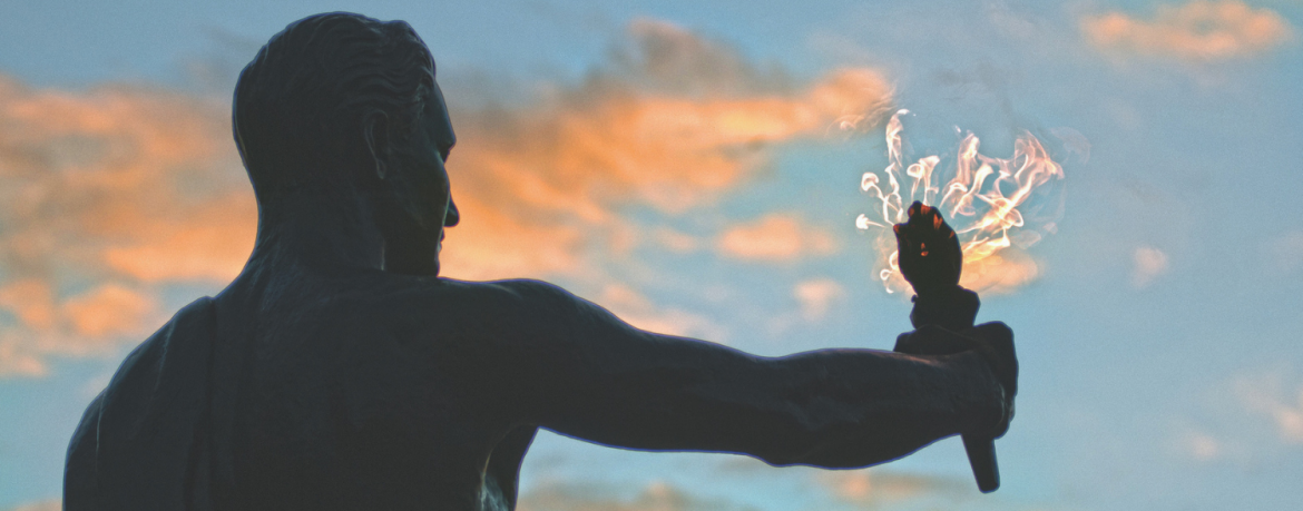 Side view of Torchbearer statue with flame against a cloudy sky
